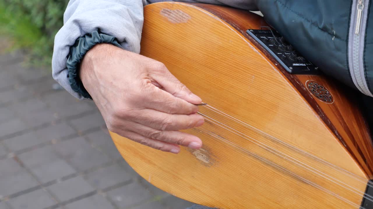A man playing a saz on the street