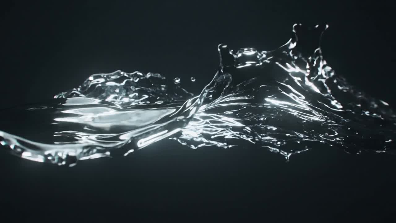 Un nastro d'acqua che si muove, attivato dal movimento, forma creste e si disperde in goccioline sotto le luci dello studio.