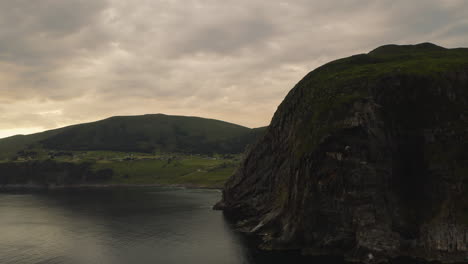 rocky cliff and green meadow at the town of maaloy in vestland county, norway
