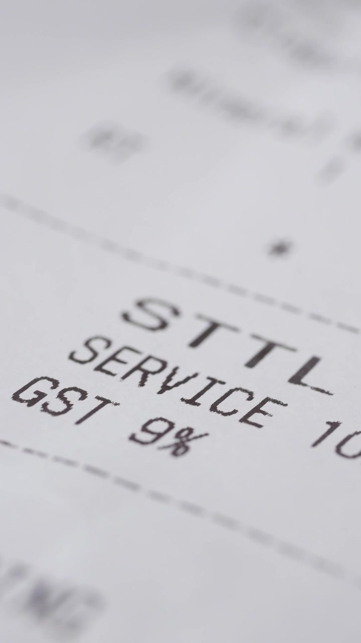 Nærbillede af en printet restaurantkvittering, der viser servicegebyr og moms.