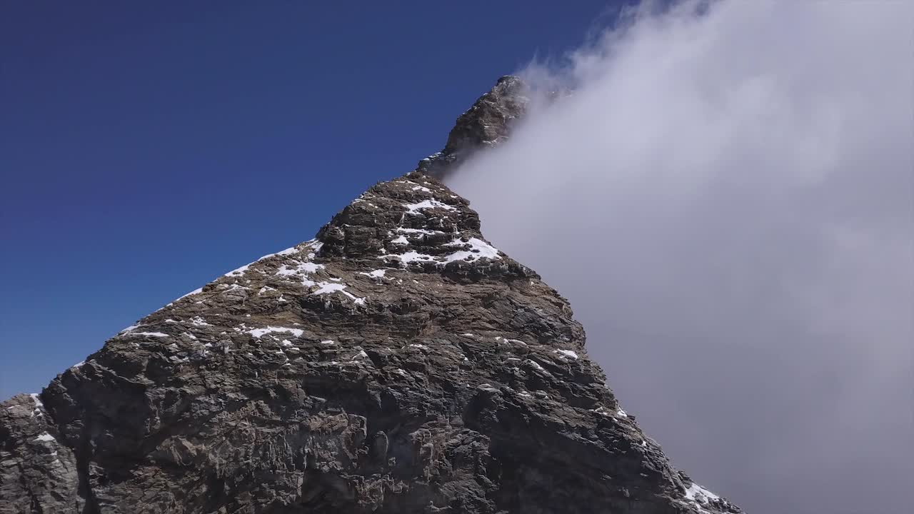 pico matterhorn con nubes ocultando un lado y cielo azul claro más allá