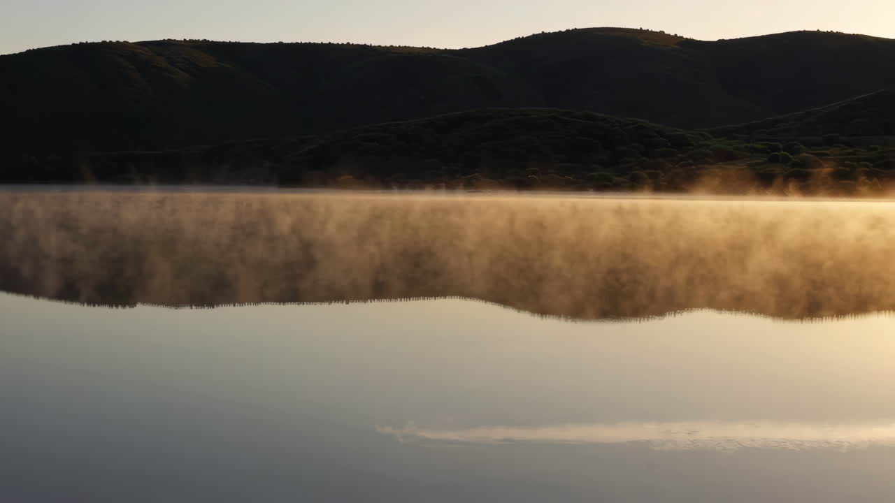 Misty Sunrise over a Lake with Mountain Reflections