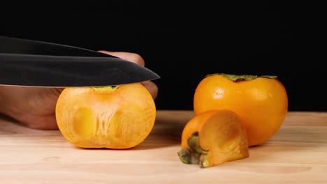 a hand carefully slices a ripe persimmon