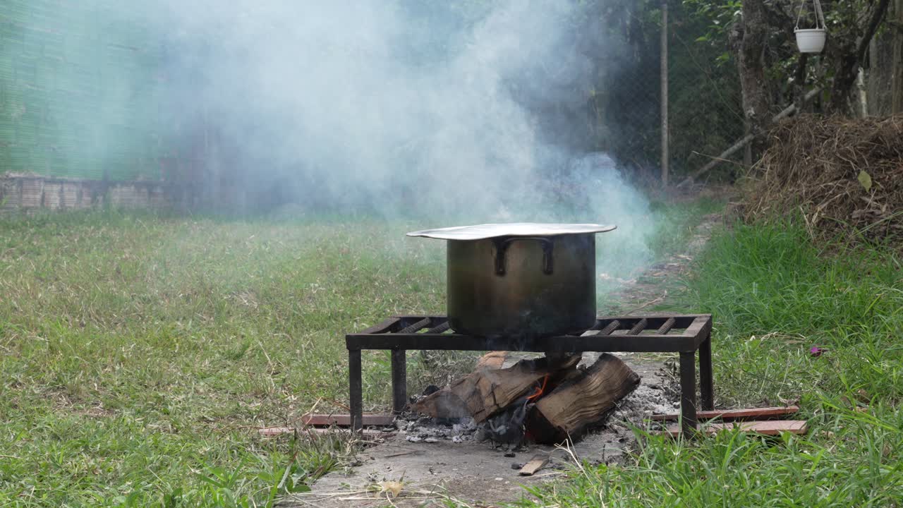 Outdoor kitchen cooking pot of food simmer over real woodfire fire camping