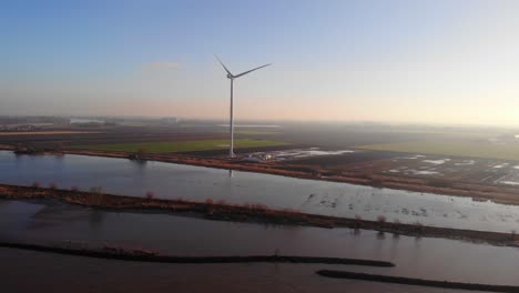 aerial view of lone new giant wind turbine next to oude maas in netherlands