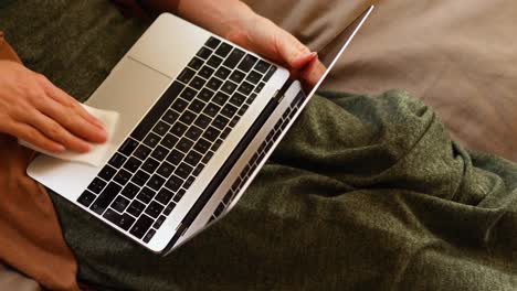 mujer caucásica lavando su computadora portátil en casa.