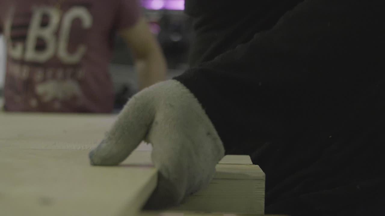 회색 장갑을 입은 사람이 나무로 일하고 있습니다.