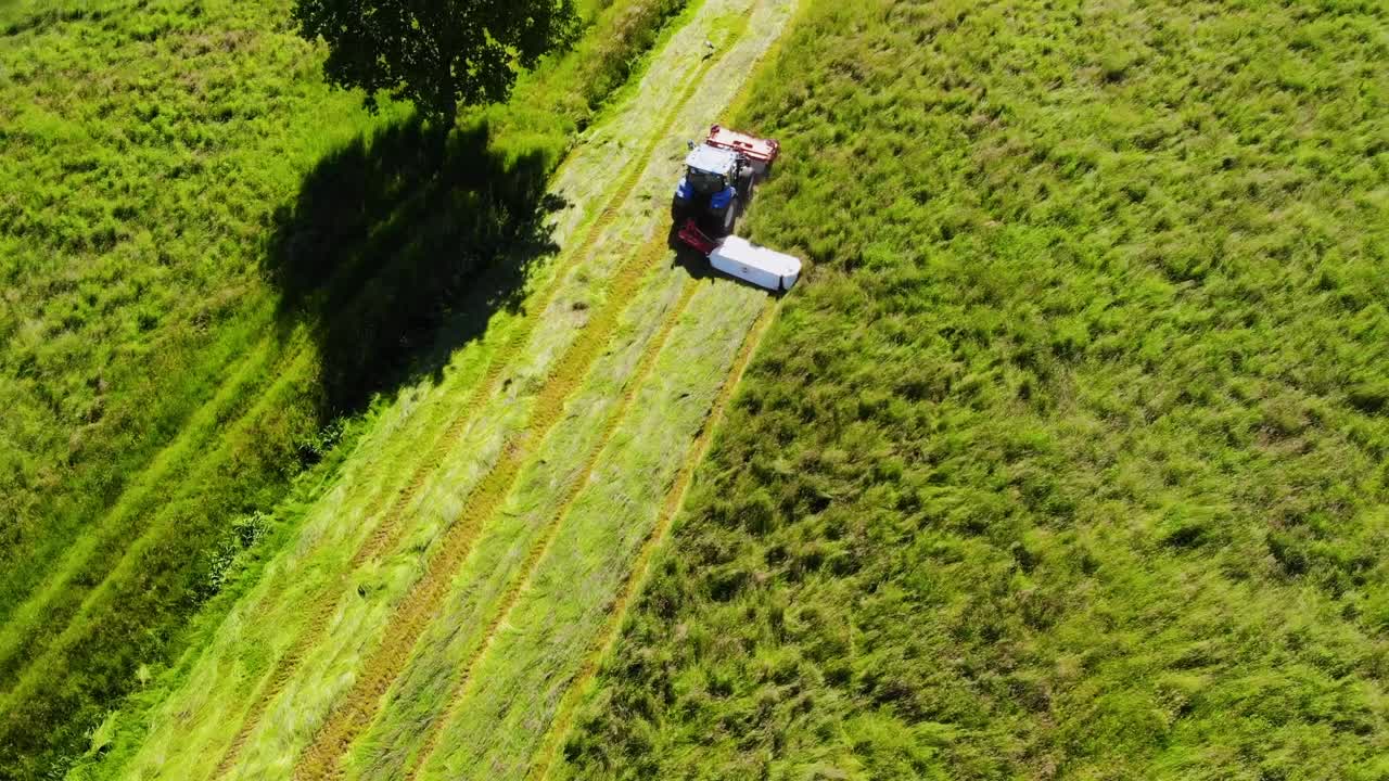 Tractor with double mower filmed during hay harvest