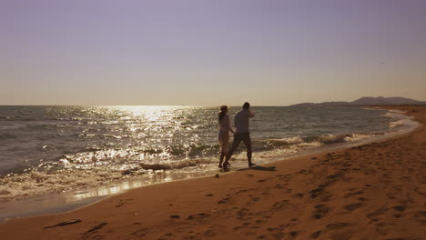 couple walking on beach at sunset