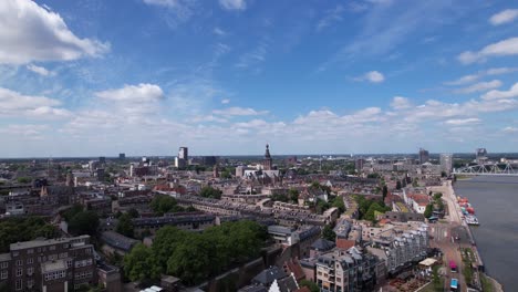 aerial ascending movement revealing cityscape of dutch historic hanseatic city center of nijmegen in the netherlands on riverbed of river maas on a sunny day partly in shadow of clouds