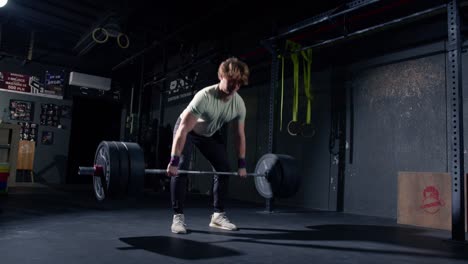 Young-caucasian-man-doing-deadlift-with-bar-in-slow-motion-inside-a-Crossfit-box