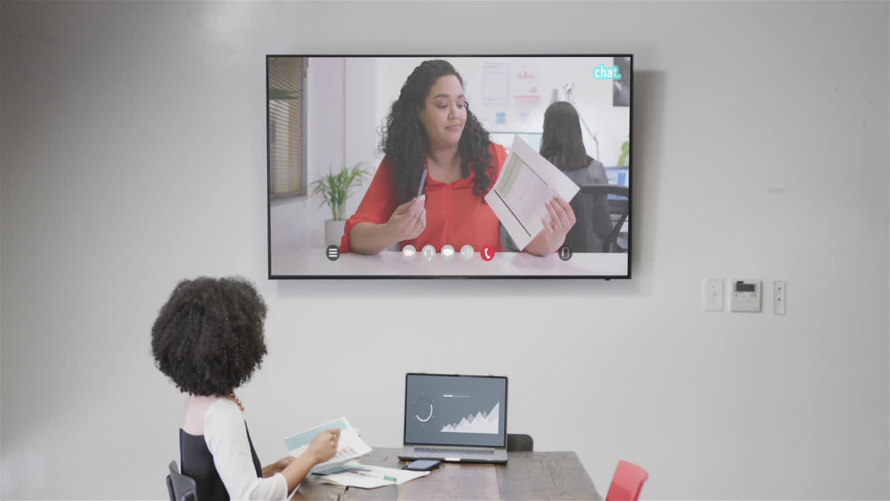 mujer de negocios afroamericana en videollamada con su colega afroamericana en la pantalla de televisión