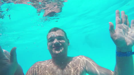 niño y padre agitando las manos al bucear en la piscina