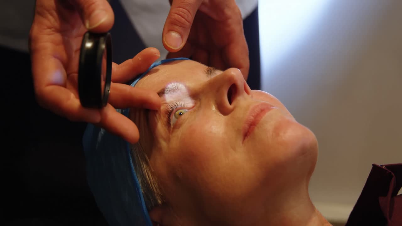 Optiker undersøger patients øjne med synstestudstyr på klinik 4k