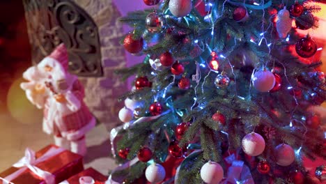 new year's gifts in red boxes with ribbons near the christmas tree with colorful balls. light leaks and flare from the festive illumination. happy holyday celebrations