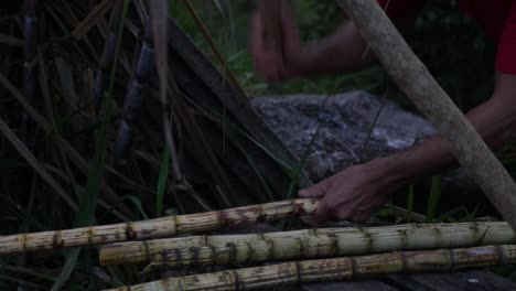 man beating sugarcane with a hammer to prepare it in slow motion