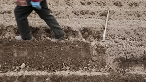 panning shot of a gardener leaving the hoe after working with the soil