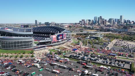 Filmische-Luftaufnahme-Des-Ikonischen-Empower-Field-Im-Mile-High-Stadium-Mit-Autos,-Die-Auf-Parkplätzen-Und-Der-Hauptstraße-Highway-Und-Der-Innenstadt-Von-Denver-Im-Hintergrund-Geparkt-Sind,-Colorado