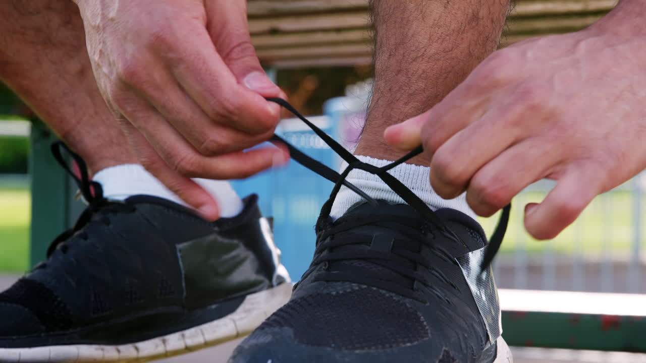 Male runner tying shoelaces outdoors, low section, detail