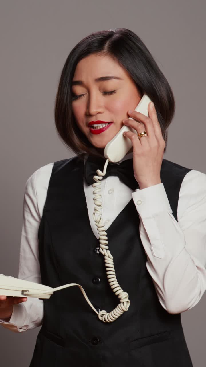 Video verticale di una receptionist asiatica che risponde a una telefonata in studio