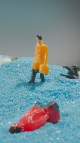 figure of worker with briefcase standing on hill surrounded by colleagues lying on blue sand. small figurine of man falling after quake macro
