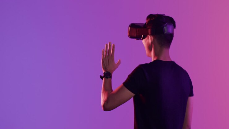 Uomo asiatico con visore VR che tocca uno schermo virtuale su sfondo viola, spazio per il testo, in slow motion.