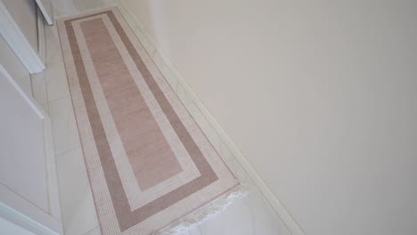 long beige and pink patterned rug on white tiled floor in a hallway