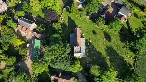 a top-down pan over st andrew's church, with surrounding houses and fields, in wickhambreaux