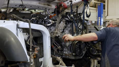 mechanic installing a new engine into a truck