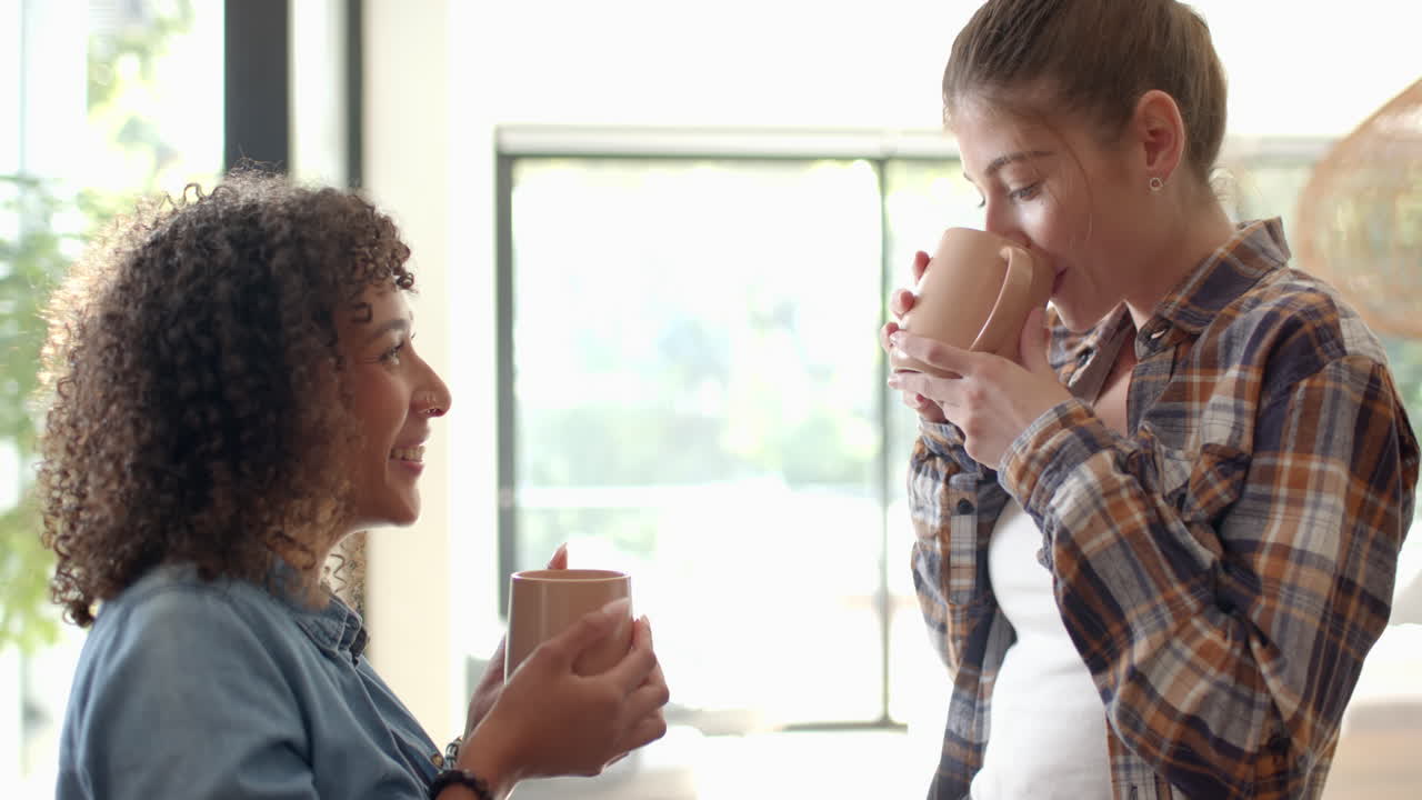 Enjoying morning together, lesbian couple drinking coffee at home