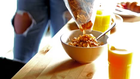 couple pouring cornflakes in bowl in kitchen