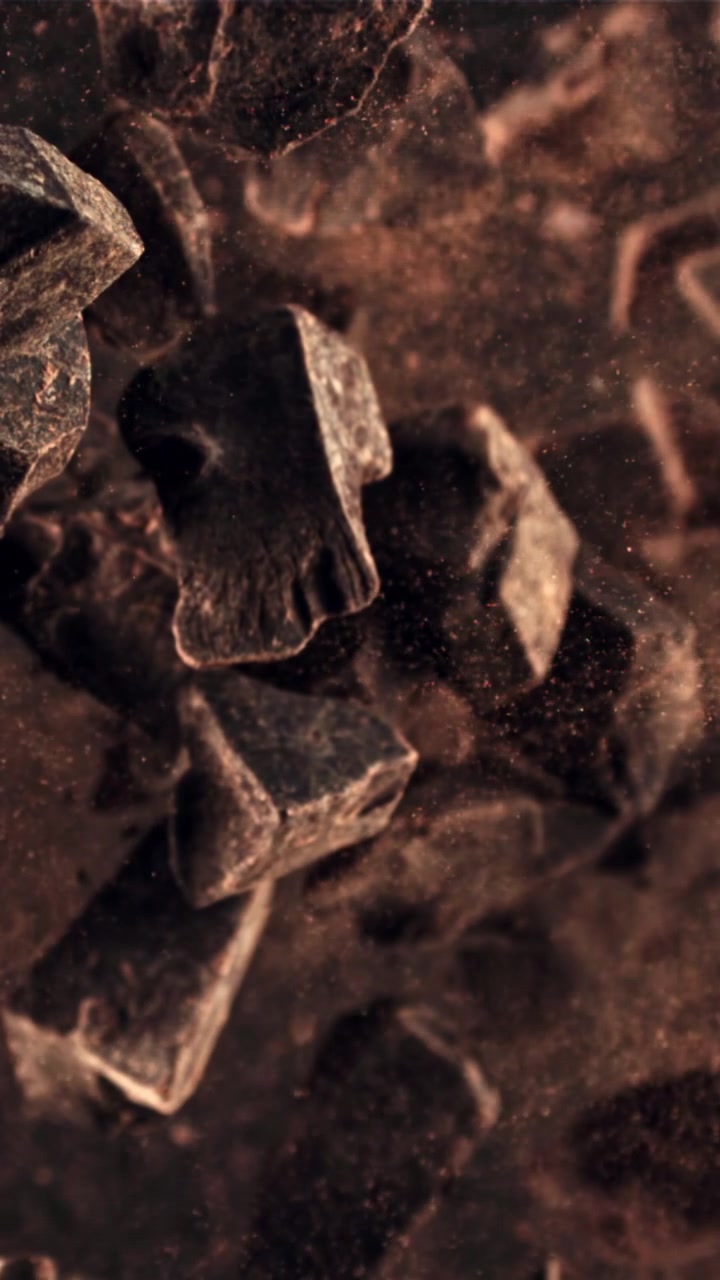 Primer plano a cámara lenta de cacao en polvo cayendo sobre trozos de chocolate negro