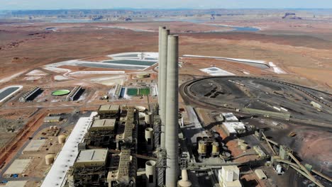 A-drone-shot-of-the-“Navajo-Generating-Station”,-a-massive-coal-fired-power-plant-and-industrial-complex-with-tall-stacks,-in-the-middle-of-the-desert-of-the-Navajo-Nation,-located-near-Page,-Arizona