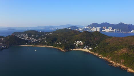 Drone-shot-traveling-forward-above-a-tropical-island-with-some-villages-and-beach-among-the-mountains-and-forest-during-a-sunny-day-1