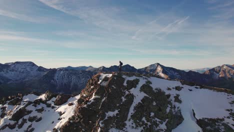 aerial orbit view of a man standing on top of a snowy mountain peak in french pyrenees