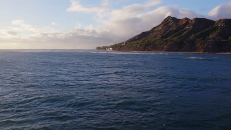 Aerial-footage-across-the-blue-Pacific-ocean-water-with-Diamond-Head-volcanic-mountain-formation-on-the-island-of-Oahu-Hawaii-on-a-sunny-day