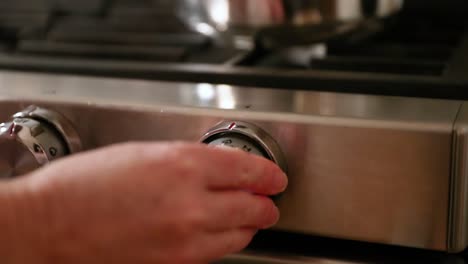 close up of woman turning on stovetop in slow motion