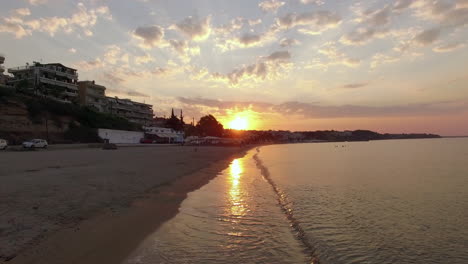 Drone-flying-along-the-coast-in-small-town-sunrise-view-Nea-Kallikratia-Greece