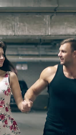 wonderful couple in summer dressing runs on underground parking lot with cars and road signs slow motion