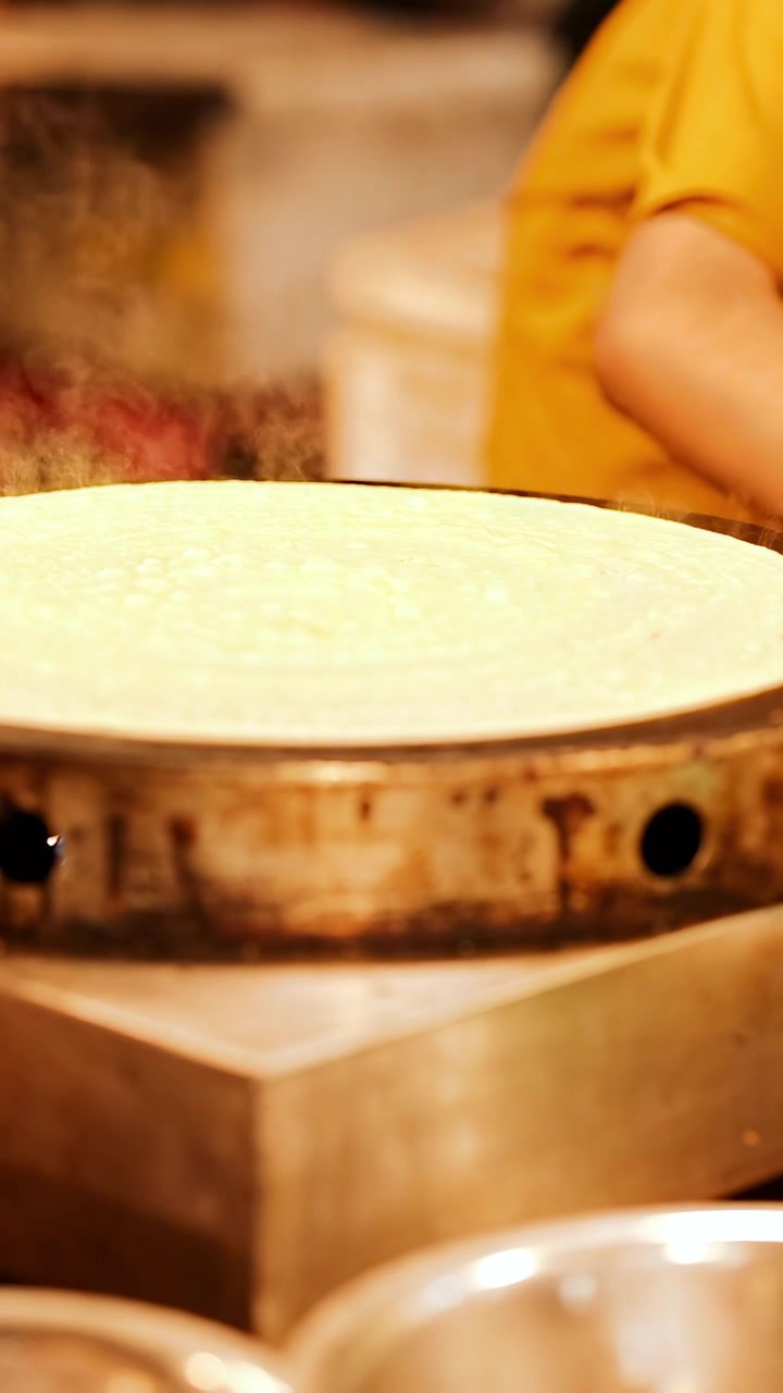 Persona che prepara crepes in una bancarella affollata del mercato di street food di Phuket