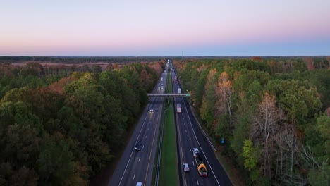 Dusk-over-a-busy-interstate-highway-among-dense-trees-in-early-fall