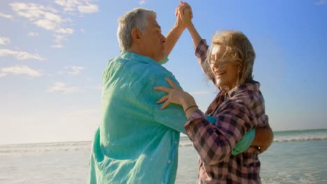 Vista-Lateral-De-Una-Pareja-Caucásica-Senior-Activa-Bailando-En-La-Playa-4k