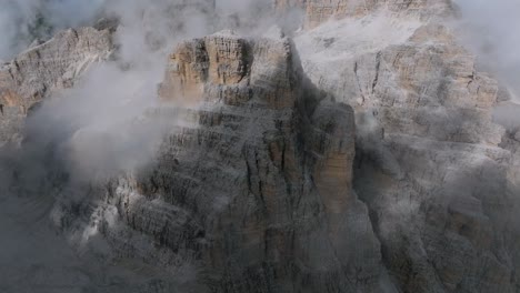 Aerial-top-down-shot-of-rocky-mountains-surrounded-by-dense-clouds-in-the-air