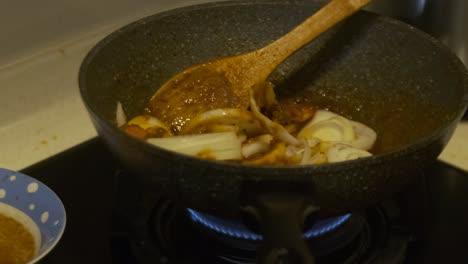 closeup of cooking chilli prawns with onions in a cooking pot on a stove