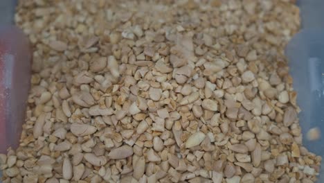 primer plano de almendras trituradas cayendo en un contenedor en una fábrica