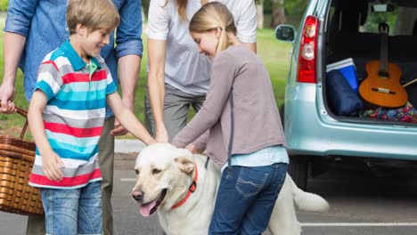 Felices-Padres-Caucásicos,-Hijo-E-Hija-Parados-Al-Lado-De-Un-Auto-Abierto-Con-Un-Perro-Mascota-En-La-Calle