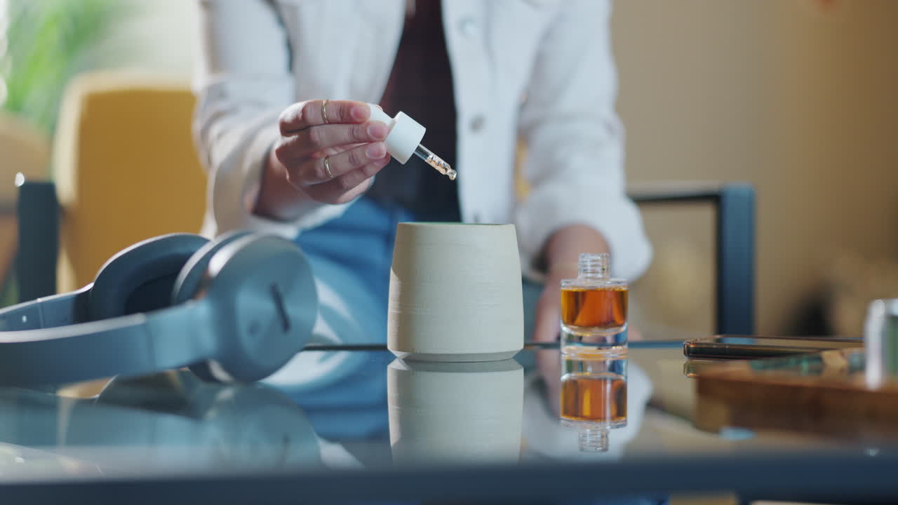 Immagine di una persona che usa un contagocce con del liquido e cuffie su un tavolo