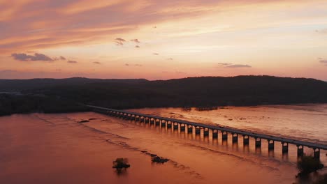 hermosa puesta de sol naranja con puente sobre un río ancho