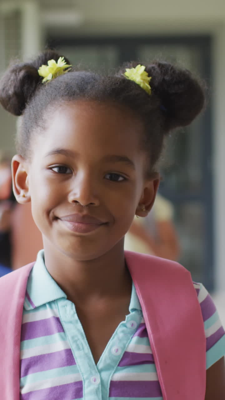 video de una feliz chica afroamericana de pie en el pasillo de la escuela