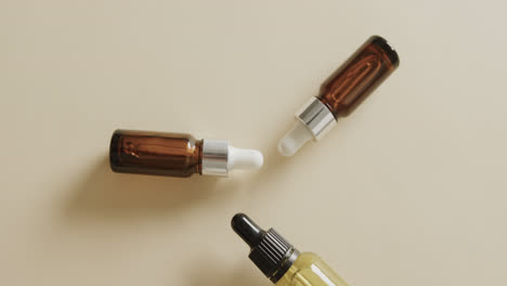 Close-up-of-three-glass-bottles-with-pumps-with-copy-space-on-beige-background-with-copy-space